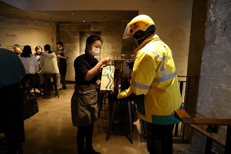 2022年1月18日,中国北京一家星巴克旗舰店,一名工作人员从美团外卖员手中接过一袋订购的食品。(路透社)