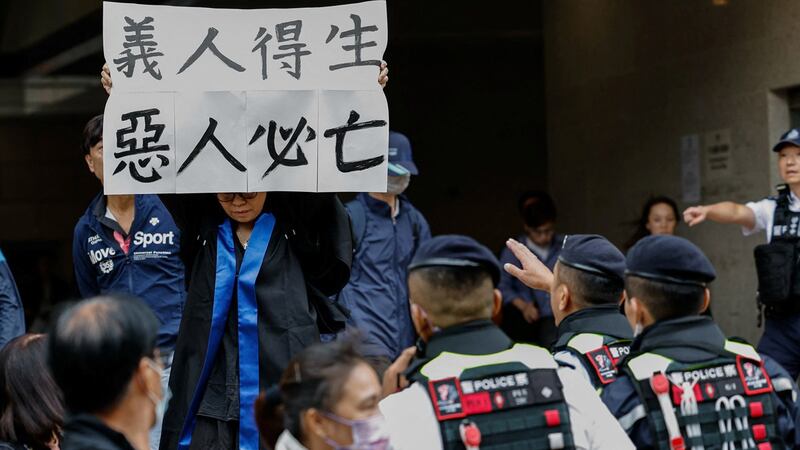 香港"四十七人案"中的吕智恒养母Elsa聆判后情绪激动,在法庭外举起"义人得生 恶人必亡"标语。 (路透社)