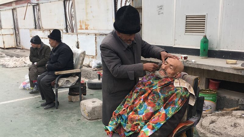 中国新疆维吾尔自治区政府发布的遏制极端主义的条例中包括：禁止男子留“不正常”的胡须，禁止妇女在公共场合穿戴掩盖全身的罩袍，或遮盖脸面的面纱。图为，2018年2月18日，一名理发师在新疆地区喀什一清真寺外刮胡子。（法新社） 
