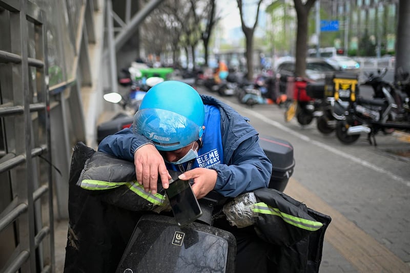 2023年4月1日,北京一名外卖员在路边休息。(法新社)