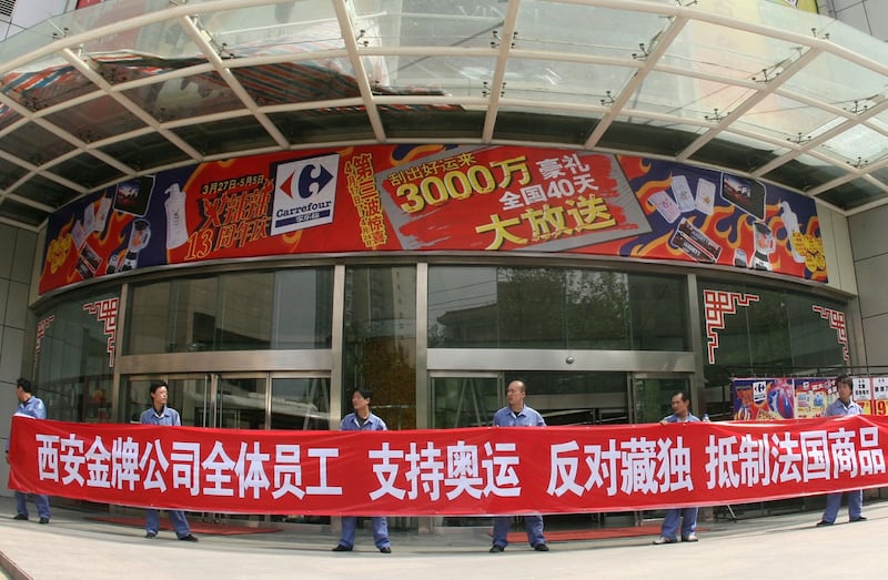 资料图片:2008年4月17日,当地公司的员工在陕西省西安家乐福超市外面举着“支持奥运会,反对西藏独立,抵制法国商品”的横幅。(路透社)