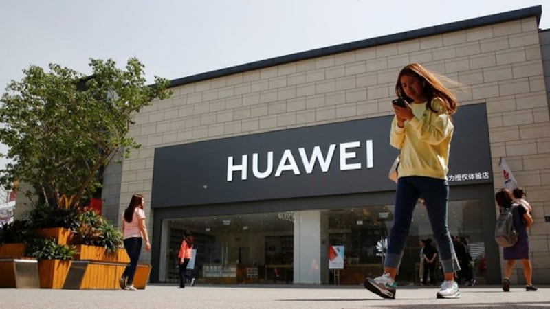 2019年5月16日,一名女子手拿手机走过北京一家华为商店。(路透社)