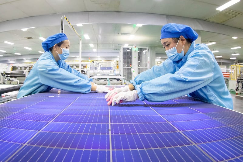 2023年11月21日,江苏省海安市一家工厂的员工正在制作生产太阳能光伏组件。(法新社)