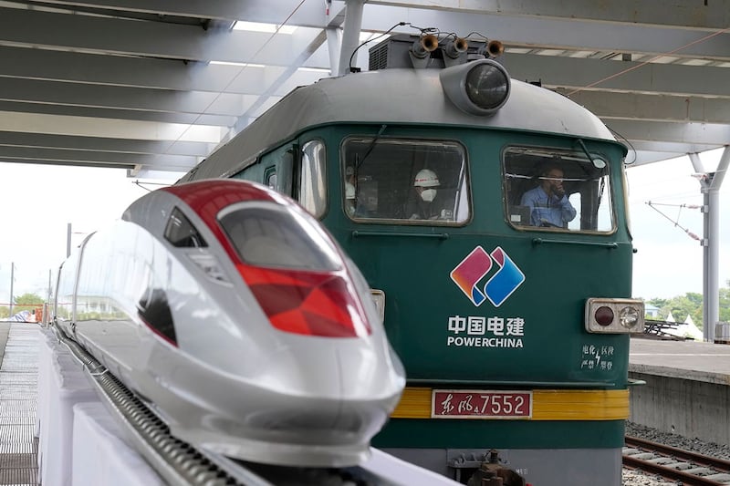 2022年10月13日,在印度尼西亚西爪哇省 Tegalluar 的雅加达-万隆快速火车站的建筑工地上,一辆火车引擎驶过展示的高速列车模型。(美联社)