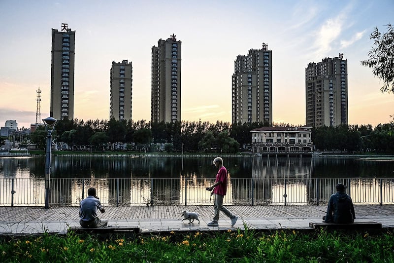 2023年7月4日,黑龙江省鹤岗市,人们在住宅楼附近的湖边休息。(法新社)