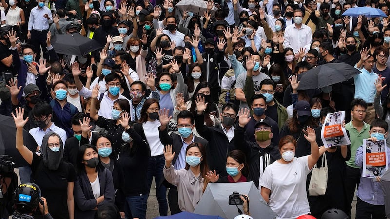 2019年11月12日,香港办公室工作人员和亲民主示威者举起5只手指,代表“五大诉求,缺一不可”。(美联社)