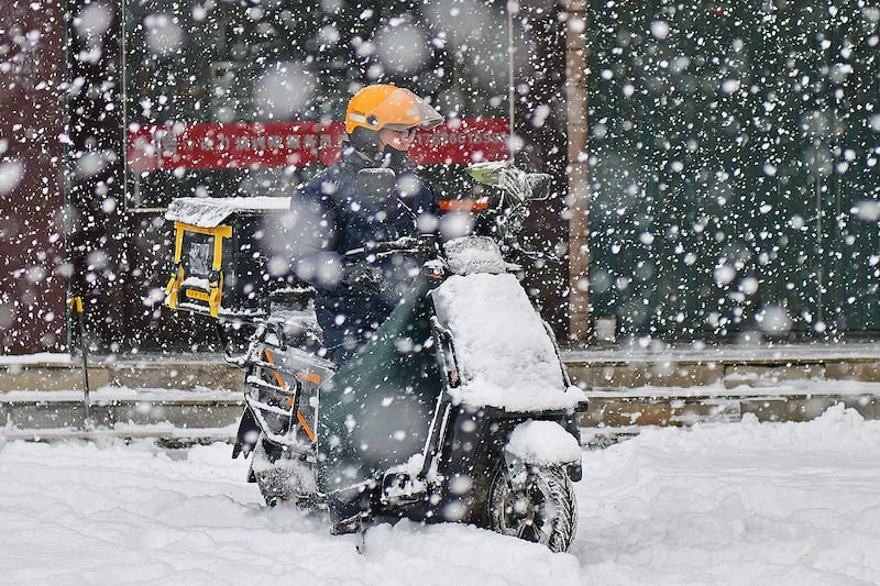 2023年12月20日,山东烟台,一名外卖骑手在雪中行驶。(法新社)